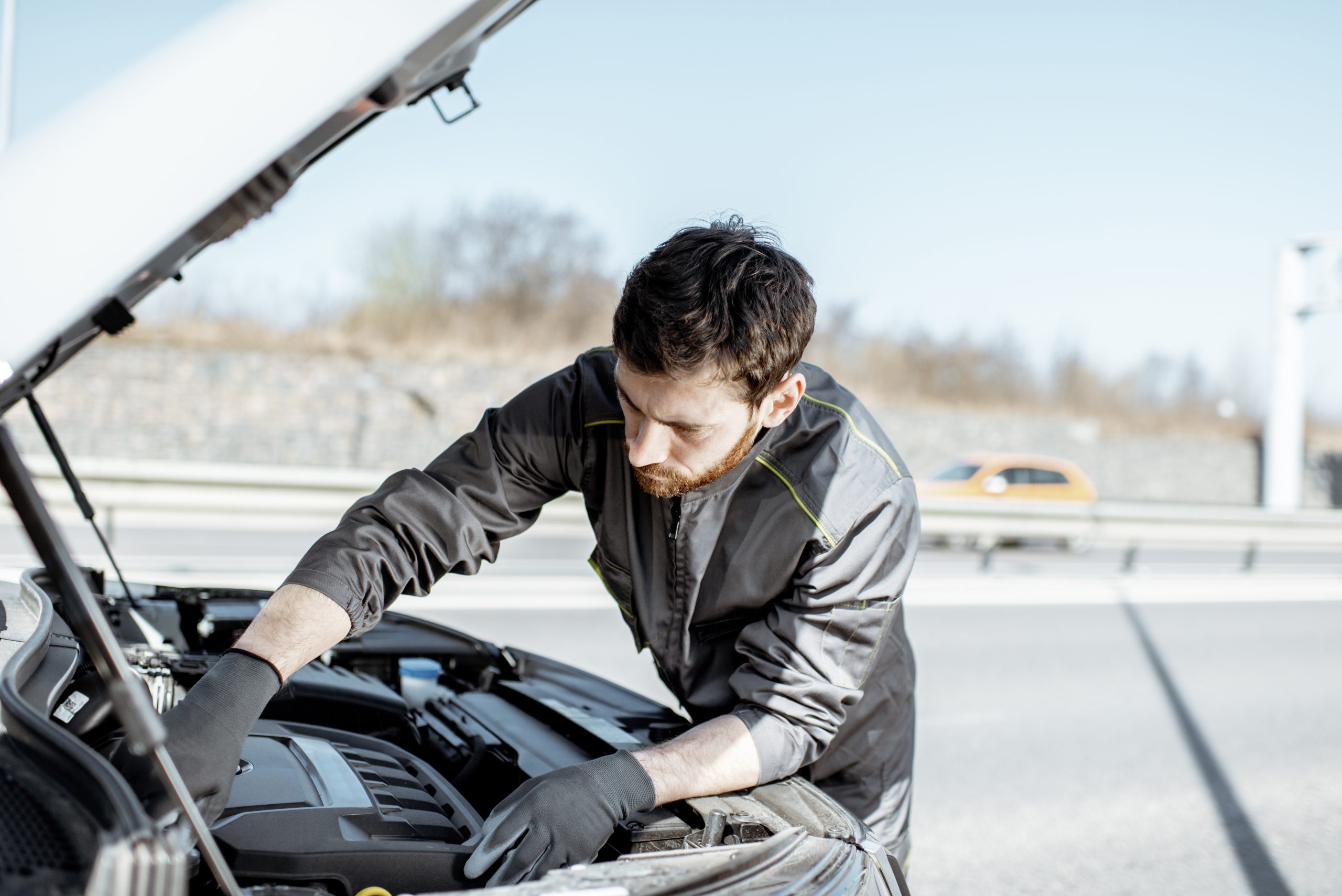Technician inspecting a car engine outdoors